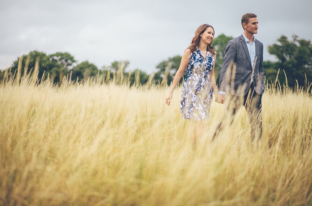 Couple holding hands walking through long grass